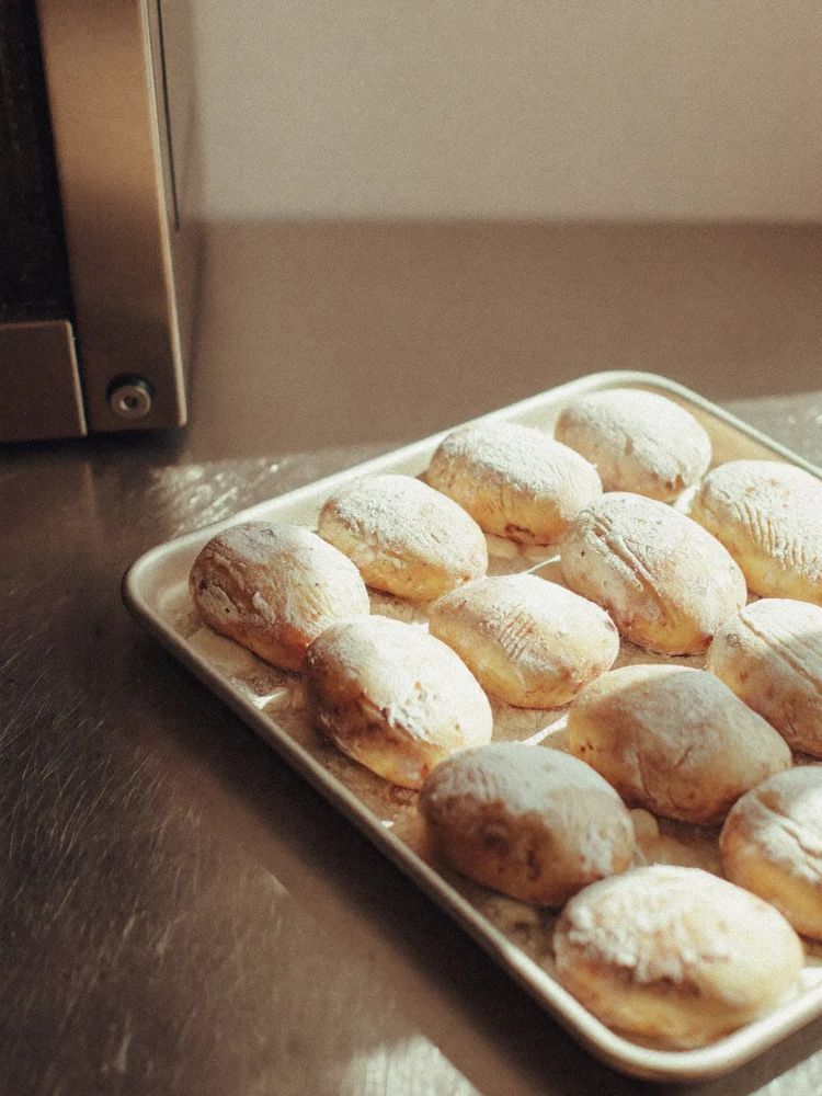 A tray of freshly baked jacket potatoes on a steel counter